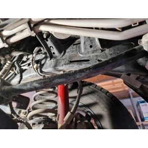 Vedere a zonei de fixare a scutului motor pe un Jeep Wrangler JL (2018+), cu amortizorul vizibil.