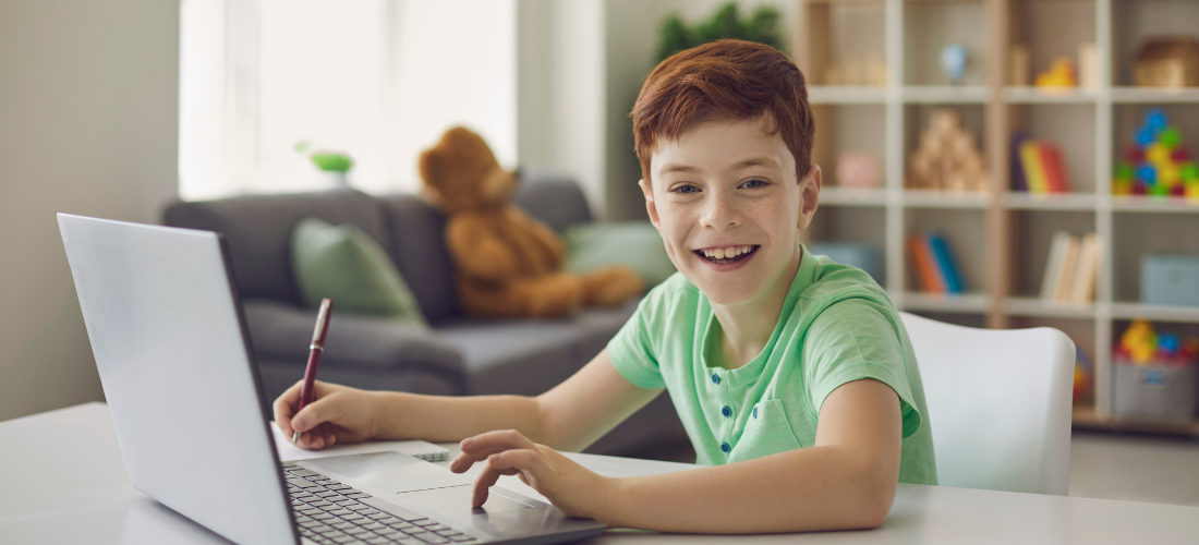 Srećno dete sedi za radnim stolom na ergonomskoj stolici i uči