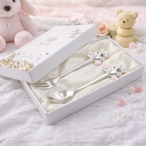 Set de tacâmuri pentru copii AZAY (linguriță + furculiță, 14,5 cm), cu design adorabil ursuleț roz, livrat în ambalaj cadou premium – cutie elegantă și tissue paper, ideal pentru botez sau aniversare.