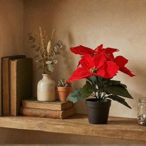 Artificial Poinsettia plant (28 cm) with red fabric petals featuring a velvety texture and green leaves, in a black pot.