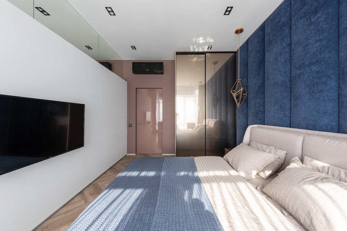 Dormitor albastru - pat pe dreapta, televizor tv negru, perete albastru