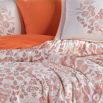 Detaliu lenjerie de pat din saten bumbac cu pilotă florală oranj pe fundal alb și cearșaf oranj uni