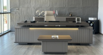 Birou managerial ORVEN Executive amplasat într-un birou office modern, culoare grej cu iluminare LED frontală și măsuță office în față