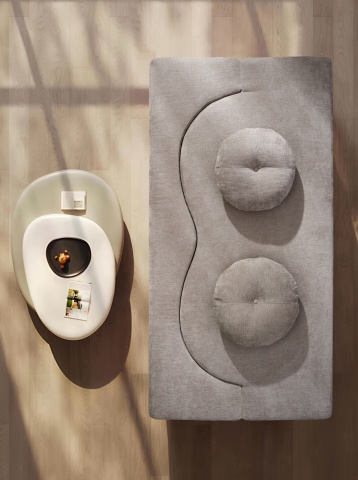 Vedere de sus: canapea gri deschis cu două perne rotunde, masă sculpturală