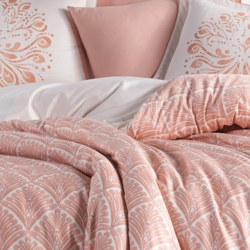 Detaliu lenjerie de pat din saten bumbac cu pilotă geometrică roz somon și fețe de pernă cu imprimeu decorativ