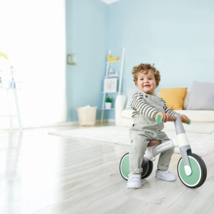 Copil pe bicicletă de echilibru Hape verde cu 3 roți – jucărie pentru dezvoltarea echilibrului.