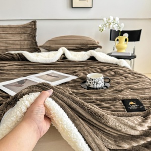 prim-plan cu mâna atingând pătura maro Jo-Jo Home, evidențiind textura 3D și blănița Sherpa de pe verso