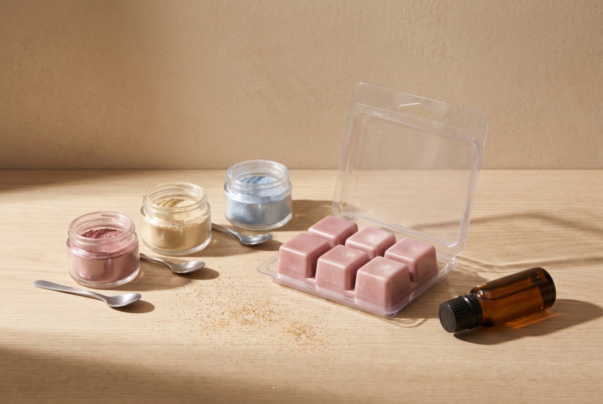 Borcănele cu pudră mica în roz, auriu și albastru, lângă wax melts colorate roz cu sclipici