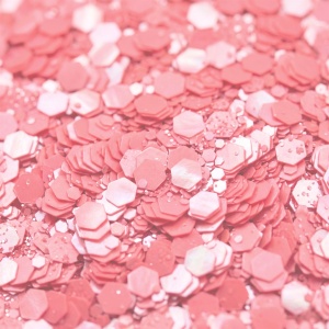 Detaliu macro cu fulgii de glitter perlat roz corai, hexagoane de mărimi diferite cu reflex sidefat
