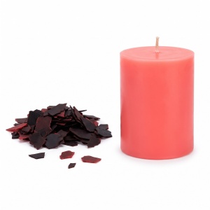Fulgi de colorant Bekro Albastru Deschis pentru lumânări, alături de o lumânare turnată în aceeași nuanță, pe fundal alb
