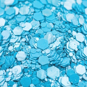 Detaliu macro cu fulgii de glitter perlat turcoaz, hexagoane de mărimi diferite cu reflex sidefat