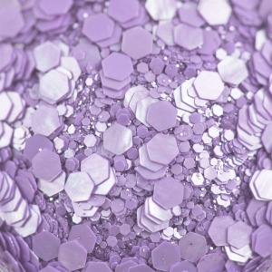 Detaliu macro cu fulgii de glitter perlat lila, hexagoane de mărimi diferite cu reflex sidefat