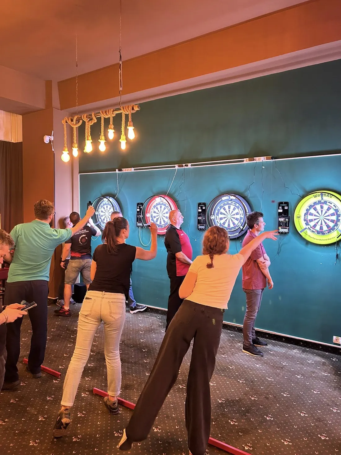 Jucători aruncând la țintele de darts, într-o seară PlayDarts