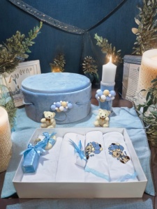 Set botez pentru băiețel în nuanțe de bleu și alb cu cutie rotundă catifelată, lumânare decorată manual și trusou complet cu model ursuleț și baloane bleu