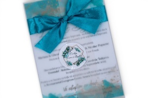 Detaliu fundiță turcoaz din satin și sticker personalizat aplicat pe invitație de nuntă.