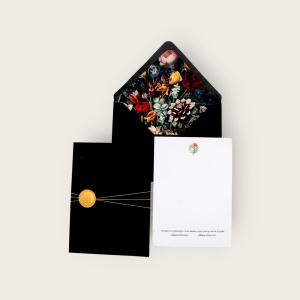 Spatele unei invitații de nuntă personalizate, alături de plic negru cu sigiliu decorativ auriu și interior floral.