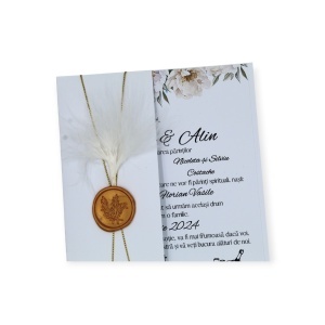 Detaliu elegant: invitație de nuntă decorată cu pene albe și sigiliu auriu premium.