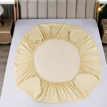 husa de culoare crem cu elastic, asezata pe pat