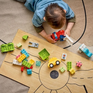 Copil construind vehicule LEGO DUPLO creative, inclusiv elicopter, camion de pompieri și autobasculantă, dezvoltând imaginația și coordonarea mână-ochi prin joacă.