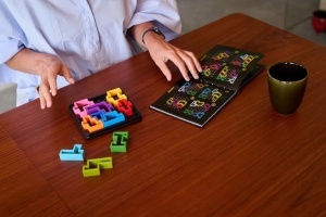 Joc IQ Deluxe Square de la Smart Games cu tablă pătrată, 10 piese puzzle decupate și broșură cu 120 de provocări logice pentru dezvoltarea gândirii spațiale și strategice.