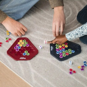 Joc Genius Gems cu două table în formă de diamant, piese colorate tip pietre prețioase cu două fețe și 9 zaruri speciale pentru provocări logice și strategice.