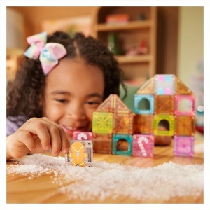 Set MAGNA-TILES microMAGS Gingerbread House cu 24 de piese magnetice colorate, ferestre, triunghiuri, elemente cu bomboane și personaj din turtă dulce.