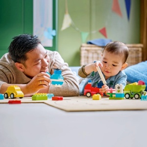 Copil construind vehicule LEGO DUPLO creative, inclusiv elicopter, camion de pompieri și autobasculantă, dezvoltând imaginația și coordonarea mână-ochi prin joacă.