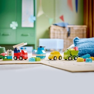 Copil construind vehicule LEGO DUPLO creative, inclusiv elicopter, camion de pompieri și autobasculantă, dezvoltând imaginația și coordonarea mână-ochi prin joacă.