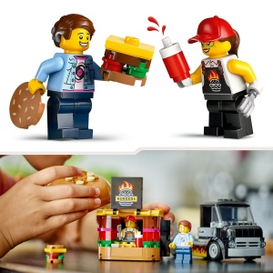 Tonetă mobilă LEGO City cu burger uriaș, camionetă și minifigurine vânzător și client, pregătită pentru aventuri culinare și jocuri de rol creative.