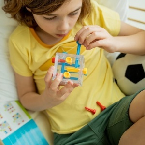 Puzzle Smart Games Criss Cross Cube cu cub transparent și 13 piese tip șurub care trebuie poziționate corect pentru rezolvarea provocărilor logice.
