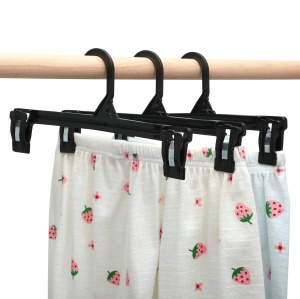 Trei umerașe cu clipsuri, ținând pantaloni albi cu imprimeu de căpșuni