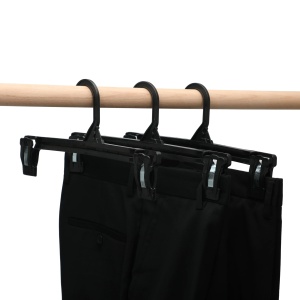 Trei umerașe cu pantaloni negri, agățate pe o bară de lemn