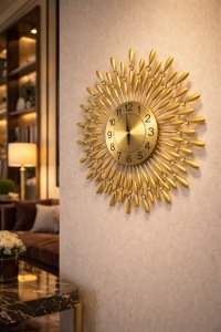 Ceas de perete auriu în formă de soare, design decorativ cu raze stilizate și accente strălucitoare