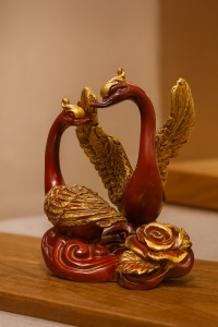 Statuetă elegantă cu două lebede aurii și roșcate, simbol al iubirii și armoniei, pe bază decorativă