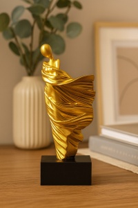 Statuetă decorativă modernă aurie, reprezentare artistică a unei femei stilizate cu rochie fluidă