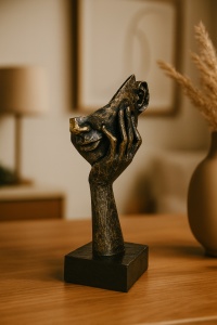 Figurină decorativă abstractă neagră cu reflexe aurii, chip sprijinit în palmă pe soclu negru