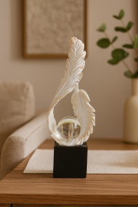 Figurină decorativă albă cu pene stilizate și glob transparent, ornament artistic pe suport negru