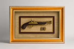 tablou cu pistol retro și gloanțe, încadrat într-o ramă aurie
