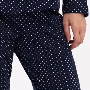 Detaliu cu banda elastică și șnurul reglabil în talie pe pantalonul albastru marin cu picățele.