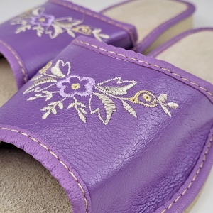Detaliu premium pe textura fină a pielii de culoare mov, evidențiind broderia florală ce aduce o notă de prospețime.