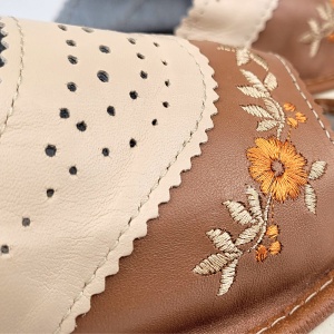 Detaliu premium cu broderia florală deosebită aplicată cu precizie pe pielea naturală fină a papucului.
