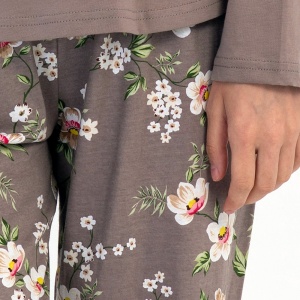 Detaliu cu banda elastică și șnurul reglabil în talie pe pantalonul cu imprimeu floral.