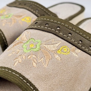 Prim-plan cu broderia florală artizanală și textura catifelată a pielii întoarse naturale.