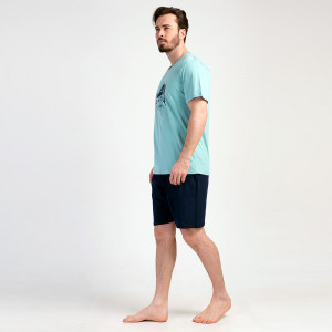 Un bărbat relaxat zâmbind purtând Pijamaua Barbati cu Pantalon Scurt Vienetta, Model Urban Silver Pine.