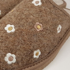 Detaliu broderie florală maro pe textura de postav maro melanj.