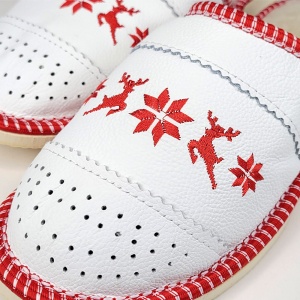 Detaliu broderie festivă de iarnă și tiv roșu accentuat pe fond alb.