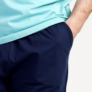 Un bărbat relaxat zâmbind purtând Pijamaua Barbati cu Pantalon Scurt Vienetta, Model Urban Silver Pine.