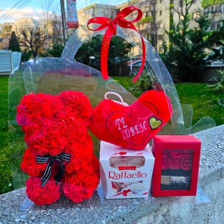Pachet Special Valentine in ambalaj transparent tip poseta cu tematica Valentine's Day, pernuta brodata "Te iubesc" 20x12 cm, ursulet din trandafiri spuma 25 cm, praline Raffaello 150 g si cutie Swet Kiss cu ruj, Rosu