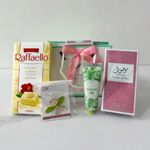 Cadou cu stil pentru femei, Spring Aromas, cu parfum arabesc Mousuf Wardi de la Ard al Zaafaran, brosa martisor, crema de maini Green Tea by Vivian Gray si ciocolata alba Raffaello New Edition, in punga cu fundita, Roz