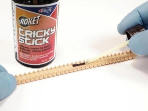 Aplicarea Deluxe Materials Tricky Stick cu pensula pe o senilă de plastic la un model RC, demonstrând amorsarea suprafeței înainte de lipirea cu adeziv cianoacrilat